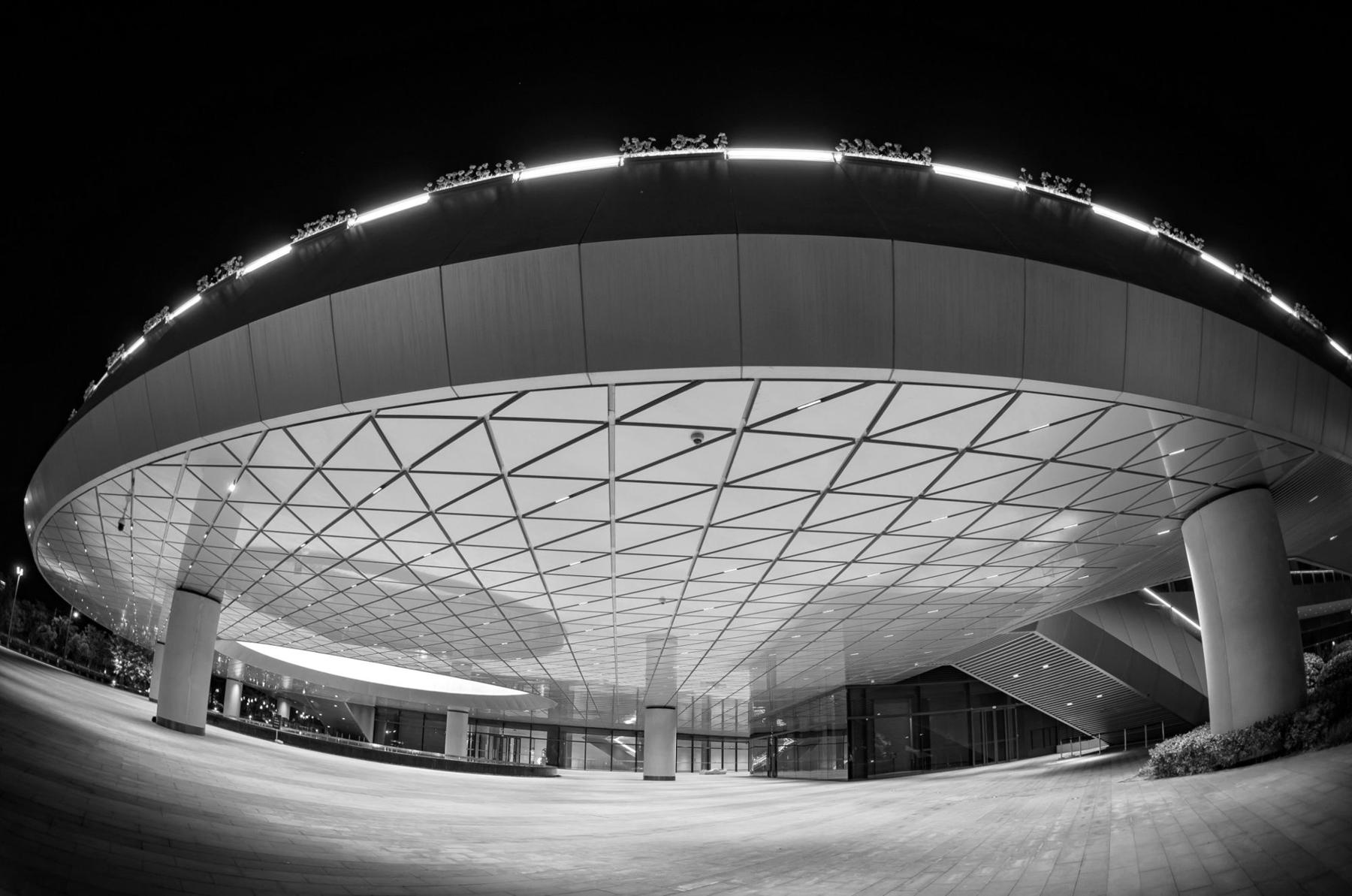 Bâtiment contemporain éclairé de nuit, bandeau lumineux continu en toiture